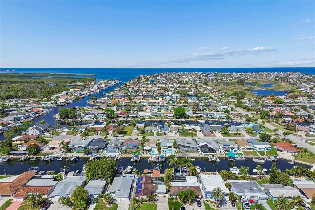 An aerial view shows a residential neighborhood with houses lining canals leading to the ocean — 4931 POMPANO DRIVE, NEW PORT RICHEY, FL