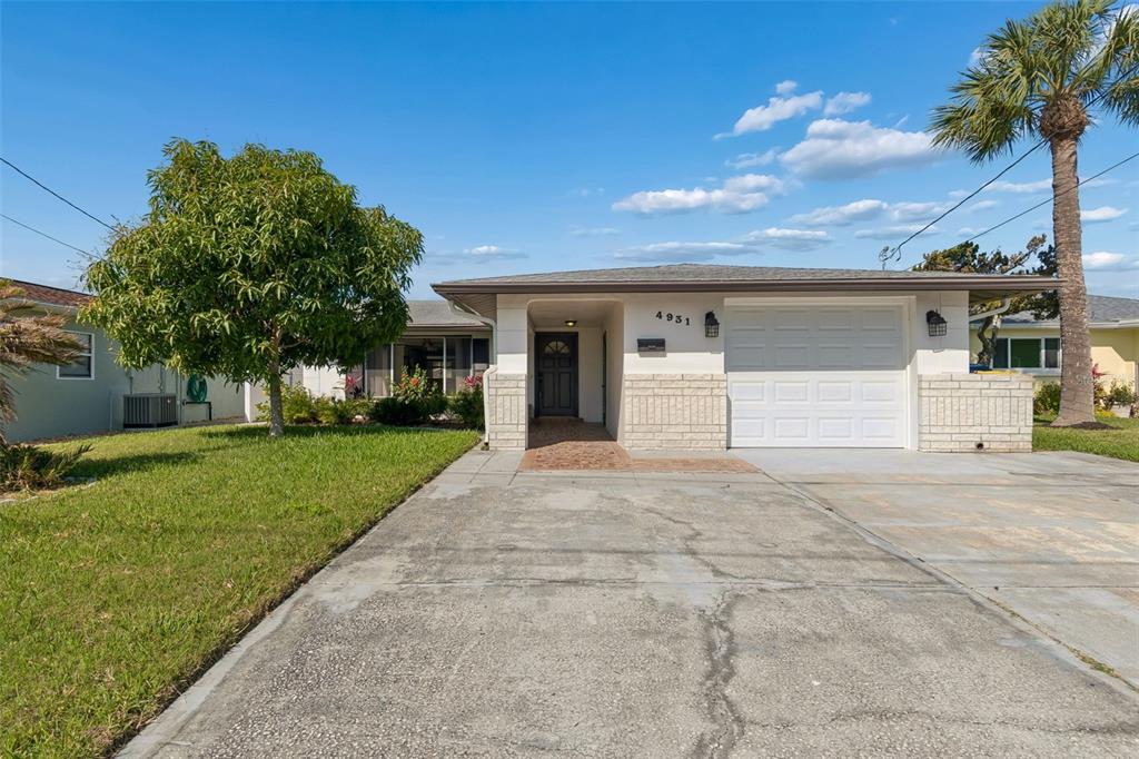 A single-story house with a white garage, a paved driveway, and a palm tree — 4931 POMPANO DRIVE, NEW PORT RICHEY, FL