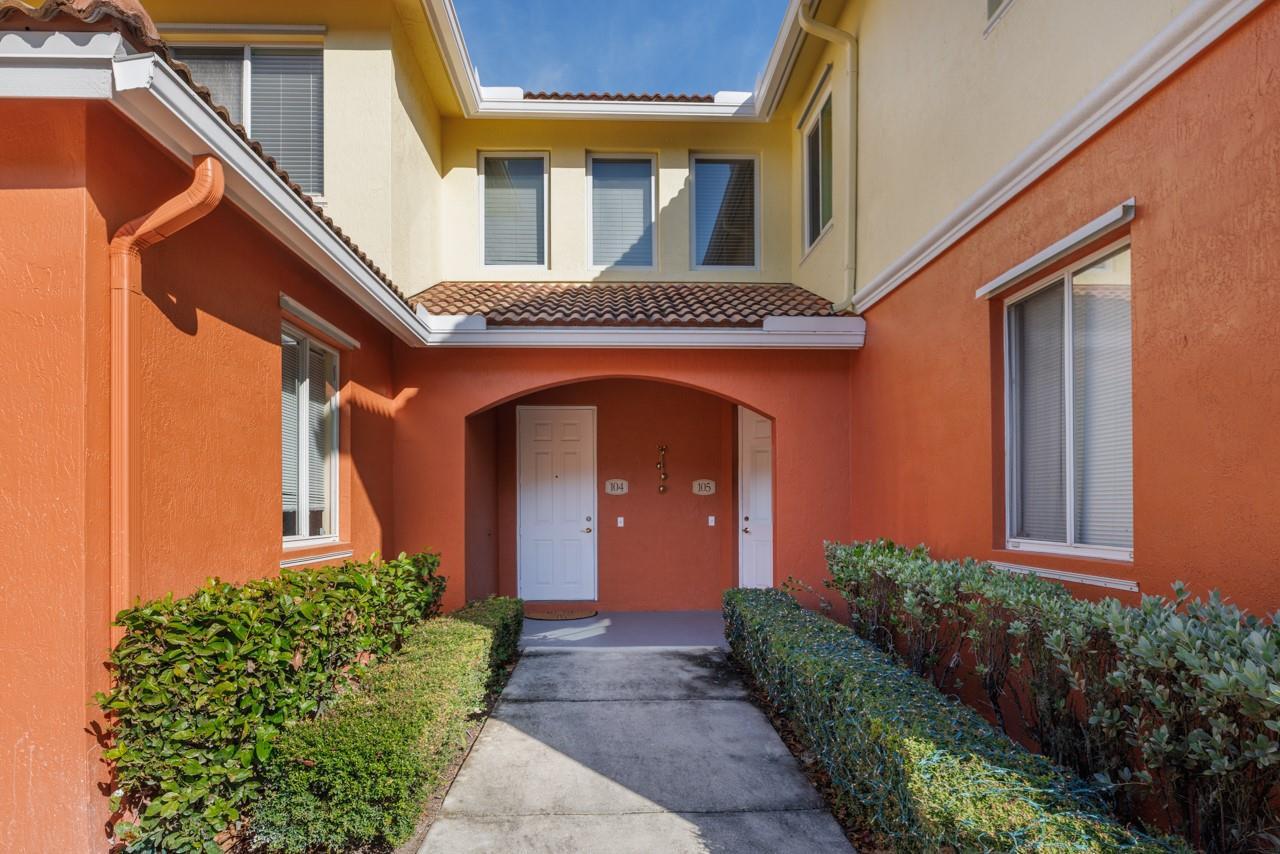 An exterior view of a two-story building with orange stucco walls and two entry doors — 55 SE Palermo Court # 105, Stuart FL 34994, STUART, FL