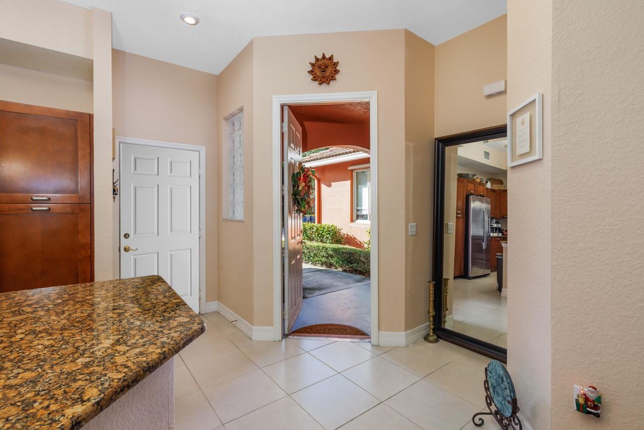 An entryway features tile flooring, a granite countertop, a large mirror, and an open door — 55 SE Palermo Court # 105, Stuart FL 34994, STUART, FL