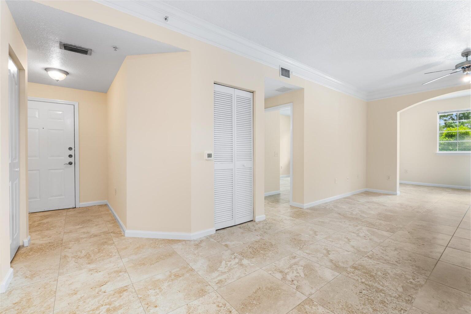 An entryway with beige tile flooring leads into a living area with a ceiling fan — 9901 Baywinds # 3105, West Palm Beach FL 33411, WEST PALM BEACH, FL