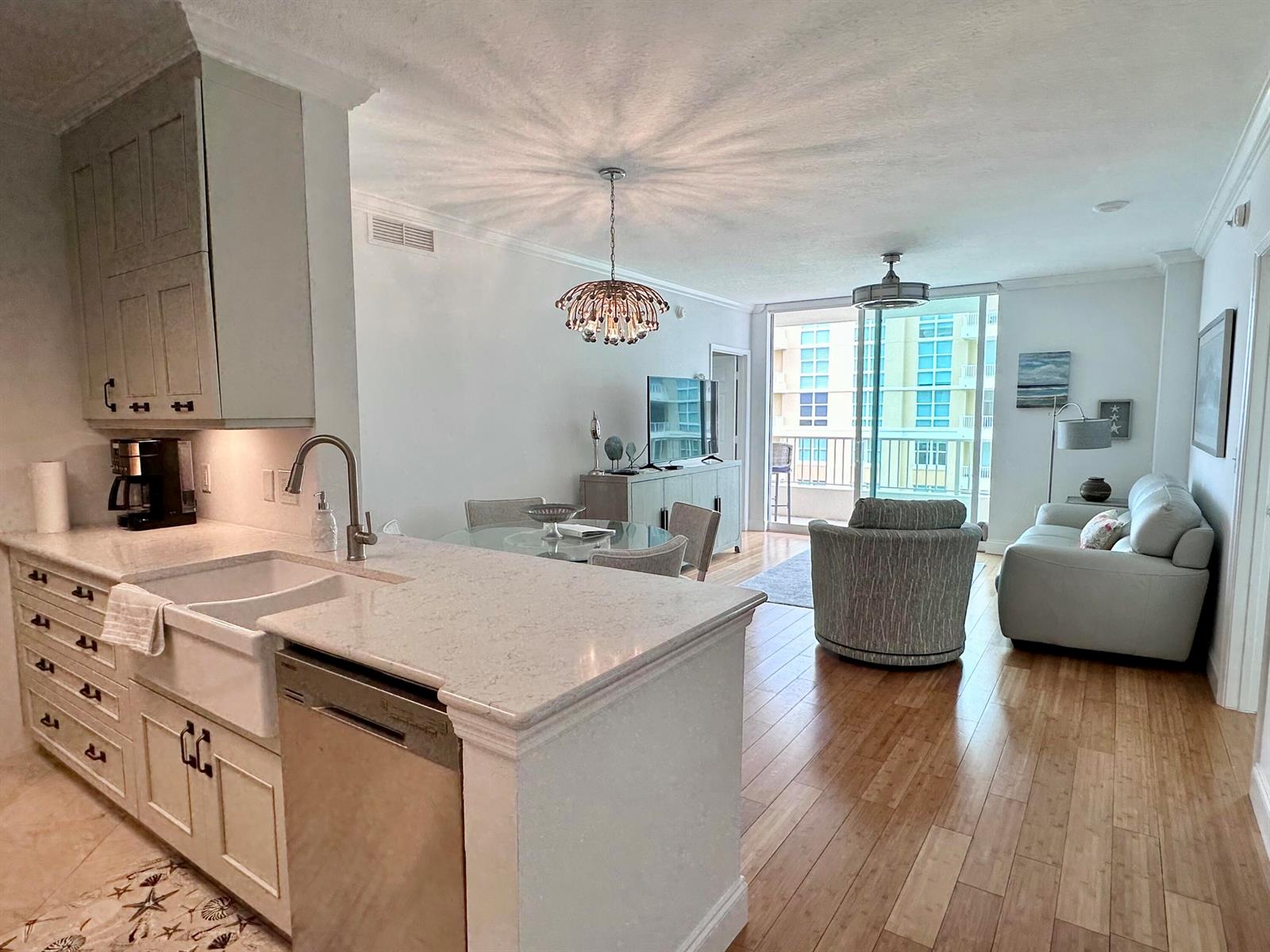 A kitchen with a farmhouse sink and island opens into a living area with balcony access — 700 E Boynton Beach Boulevard # 1203, Boynton Beach FL 33435, BOYNTON BEACH, FL