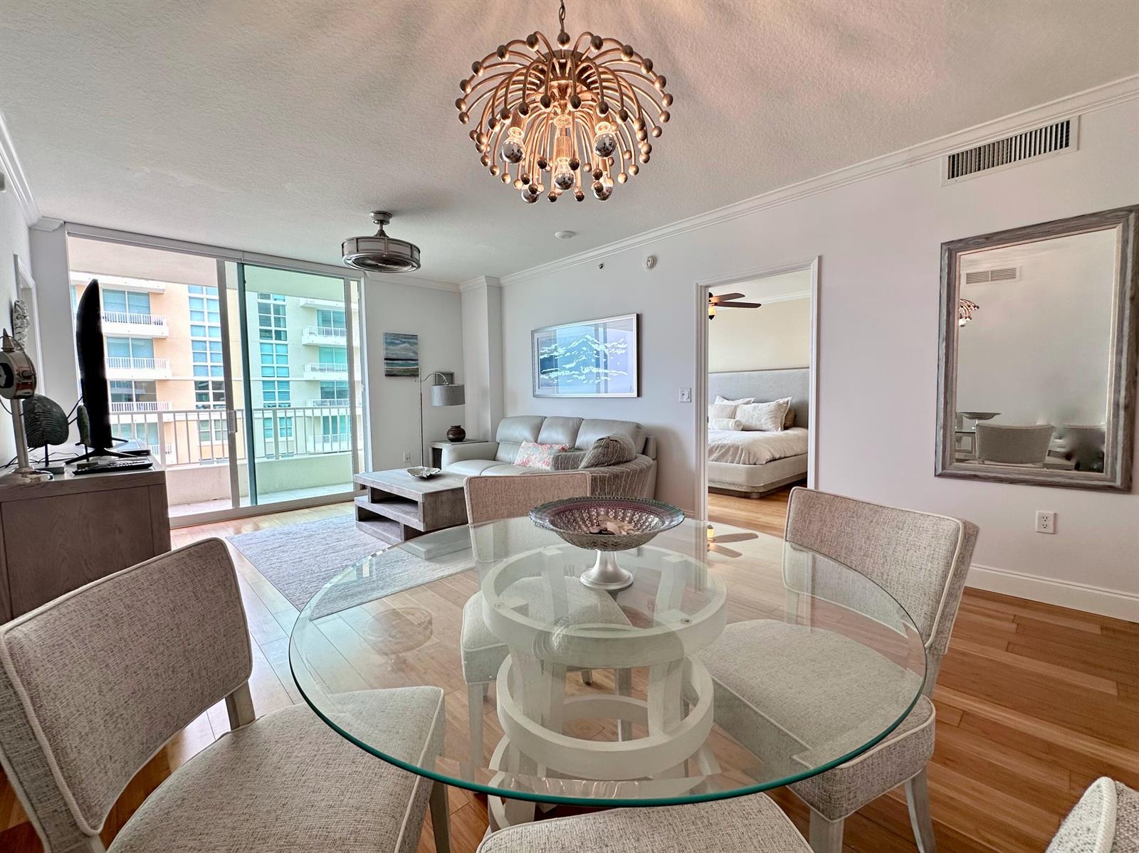 A dining area with a glass table and chandelier opens into a living room and bedroom — 700 E Boynton Beach Boulevard # 1203, Boynton Beach FL 33435, BOYNTON BEACH, FL