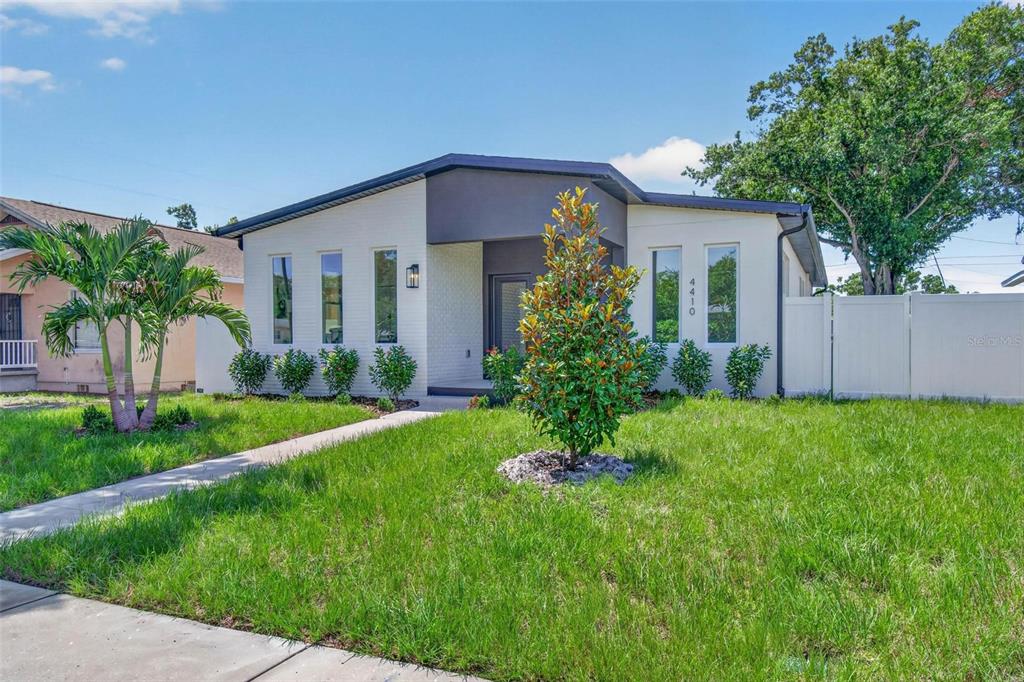 A modern, single-story house with white brick, dark gray accents, and a landscaped front yard — 4410 4TH AVENUE S, ST PETERSBURG, FL