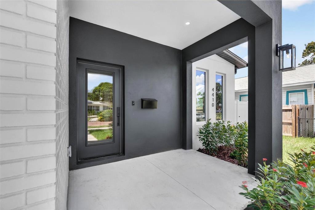A covered entryway features a dark gray wall, a glass-paneled door, and white brick siding — 4410 4TH AVENUE S, ST PETERSBURG, FL