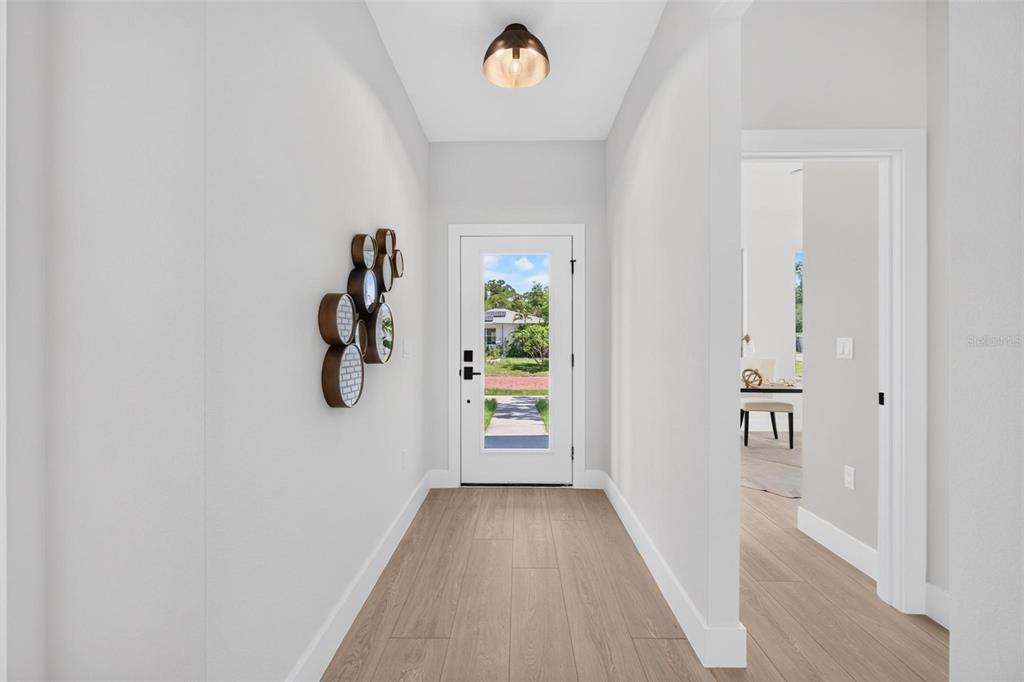 A bright entryway features light wood-look flooring, a white front door, and a modern ceiling light — 4410 4TH AVENUE S, ST PETERSBURG, FL