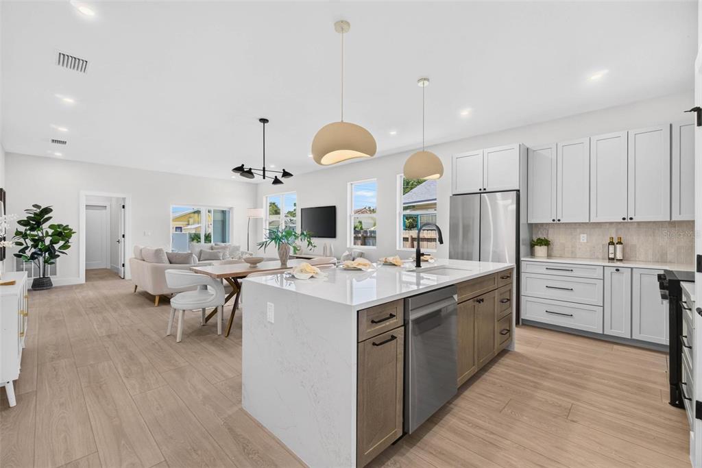 A modern open-concept kitchen features a white quartz island, light wood cabinetry, and stainless appliances — 4410 4TH AVENUE S, ST PETERSBURG, FL