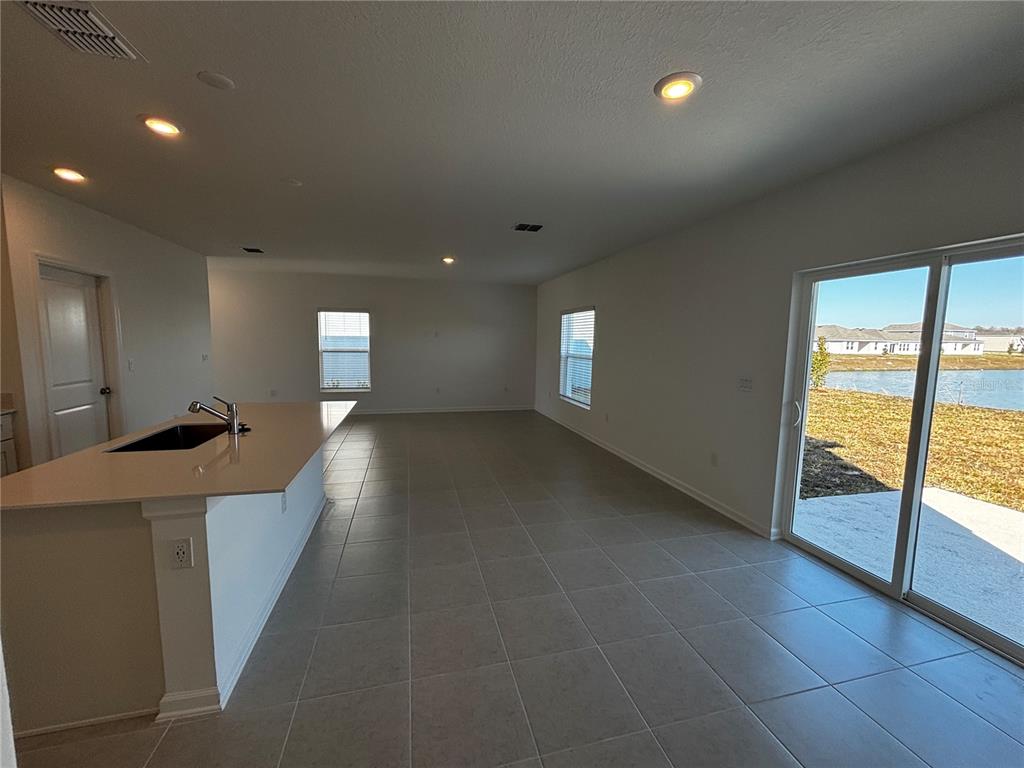 An open-concept kitchen and living area features tile flooring, a center island, and sliding doors — 4763 GUINEP LANE, KISSIMMEE, FL