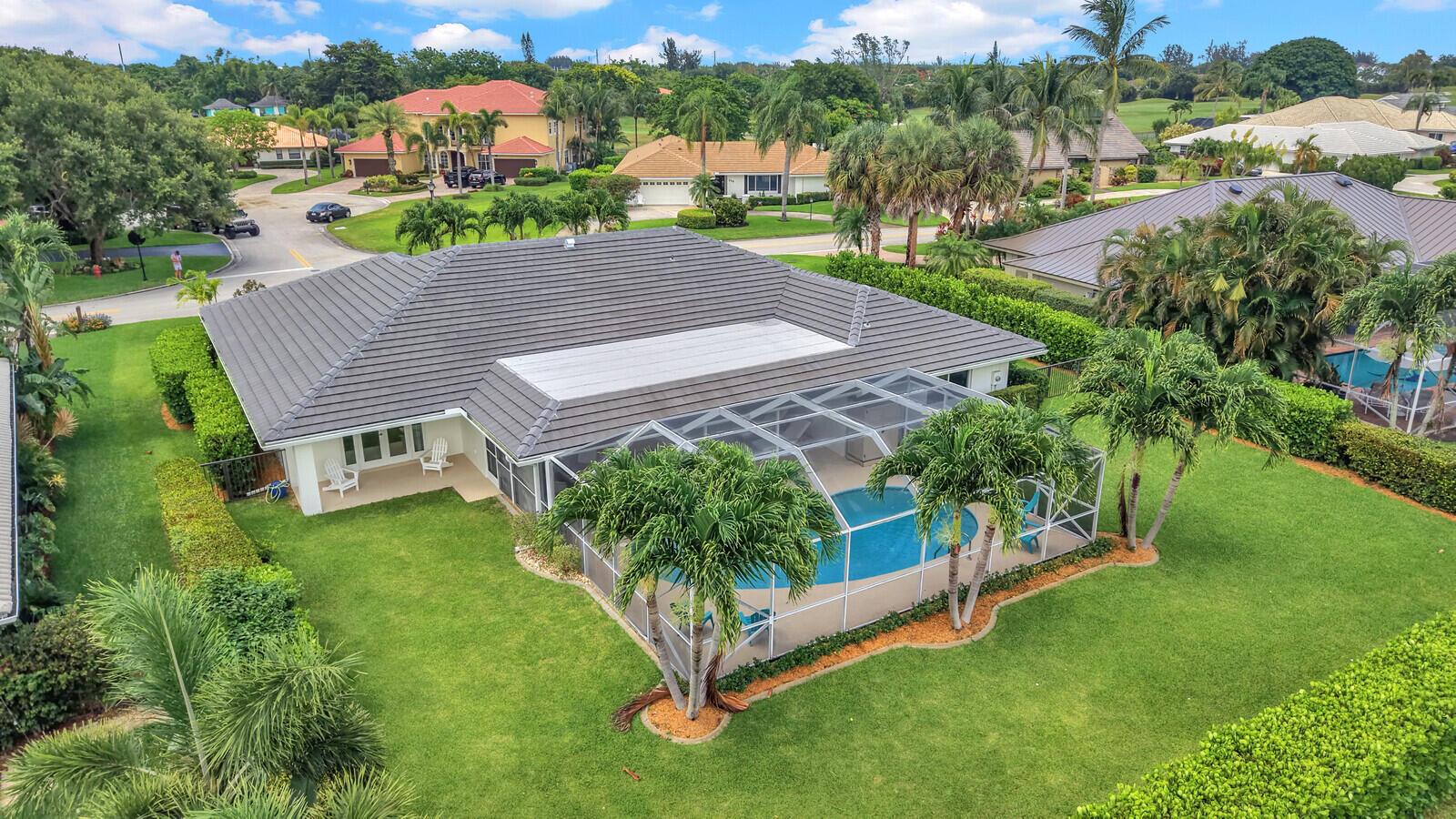 An aerial view of a house with a tiled roof, screened-in pool, and landscaped yard — 341 Glenbrook Drive, Atlantis FL 33462, ATLANTIS, FL