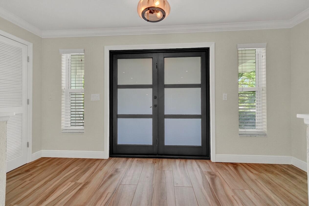 A room with wood-look flooring, two narrow windows, and a black-framed double glass door — 341 Glenbrook Drive, Atlantis FL 33462, ATLANTIS, FL