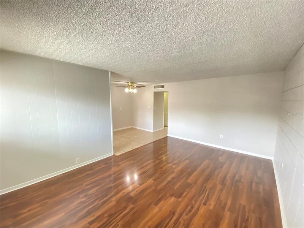 A living room with wood-look flooring, a textured ceiling, and an adjacent dining area — 320 LAKEVIEW STREET UNIT 207, ORLANDO, FL