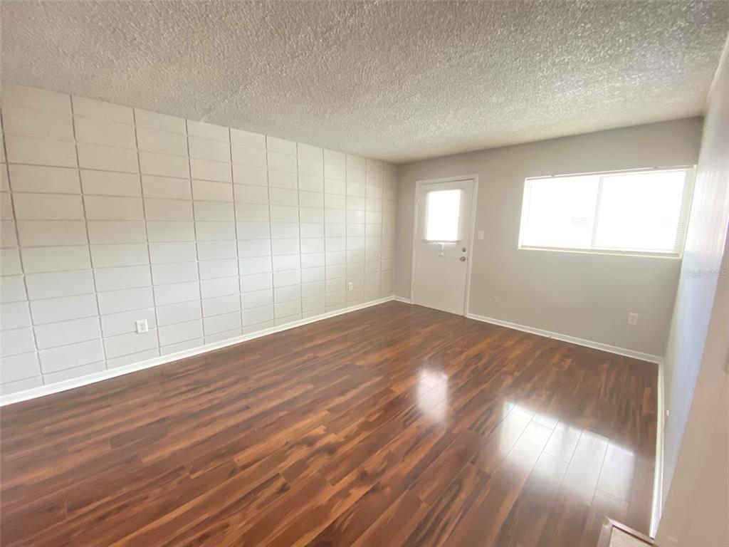 An empty room features wood-look flooring, a white paneled wall, and a single window — 320 LAKEVIEW STREET UNIT 207, ORLANDO, FL