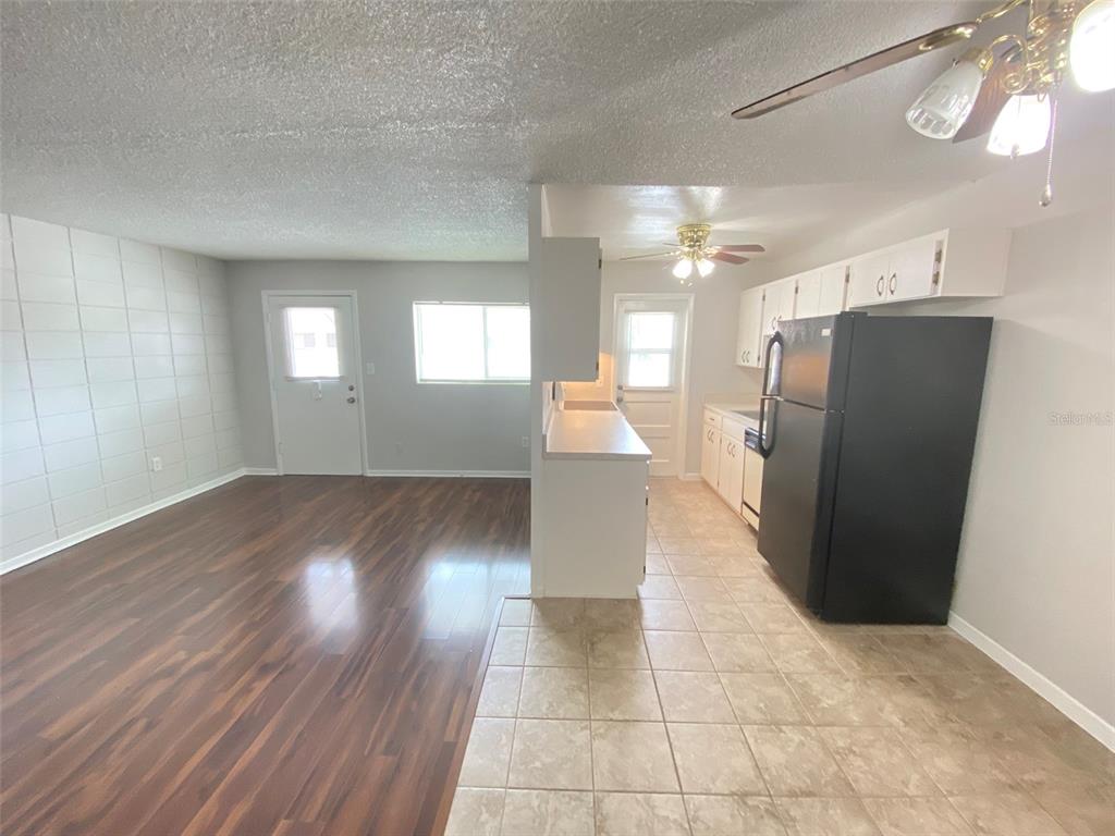 A view of a kitchen with tile flooring and an adjacent living area with wood flooring — 320 LAKEVIEW STREET UNIT 207, ORLANDO, FL