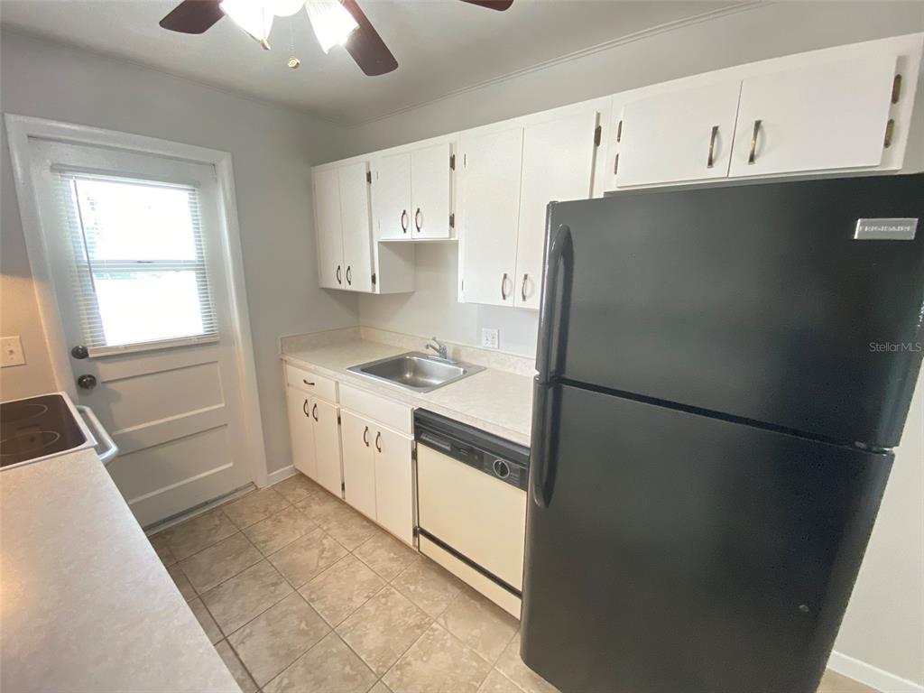 A kitchen features white cabinets, a black refrigerator, a dishwasher, and a tile floor — 320 LAKEVIEW STREET UNIT 207, ORLANDO, FL