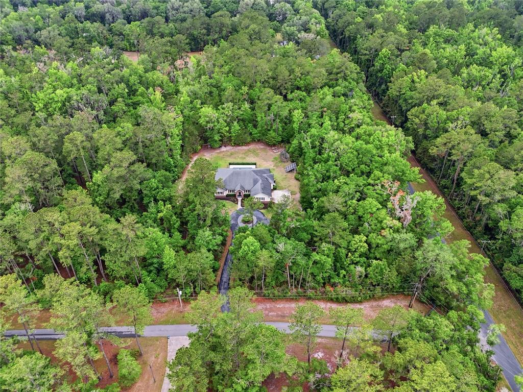 A single-story house with beige siding, red brick accents, and a circular driveway — 9208 NW 64TH TERRACE, GAINESVILLE, FL