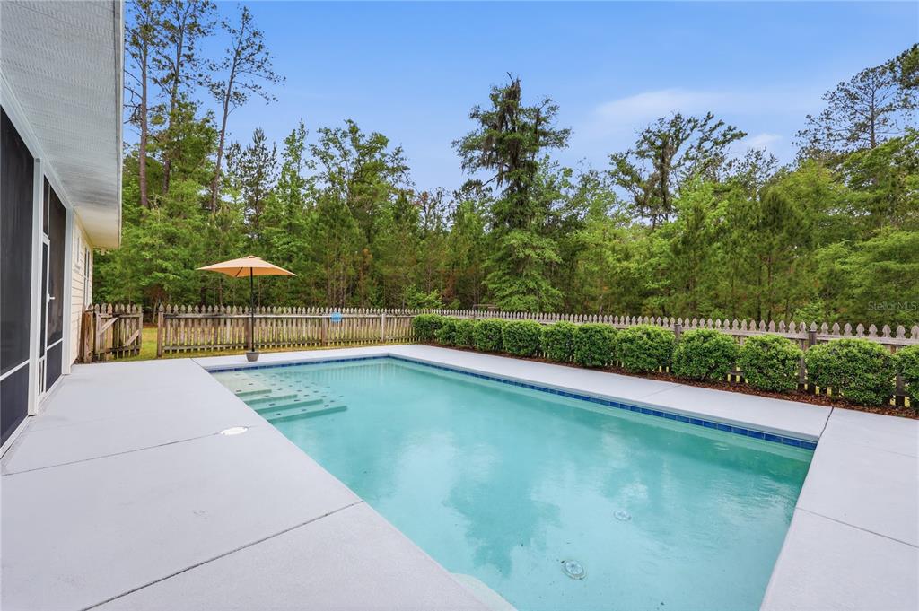 An aerial view shows a house surrounded by dense forest with a long driveway — 9208 NW 64TH TERRACE, GAINESVILLE, FL