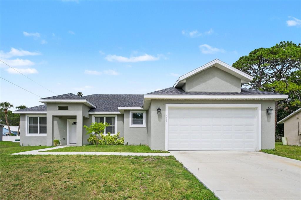 A single-story house with a gray stucco exterior, a white garage door, and a driveway — 333 KRASSNER DRIVE NW, PALM BAY, FL