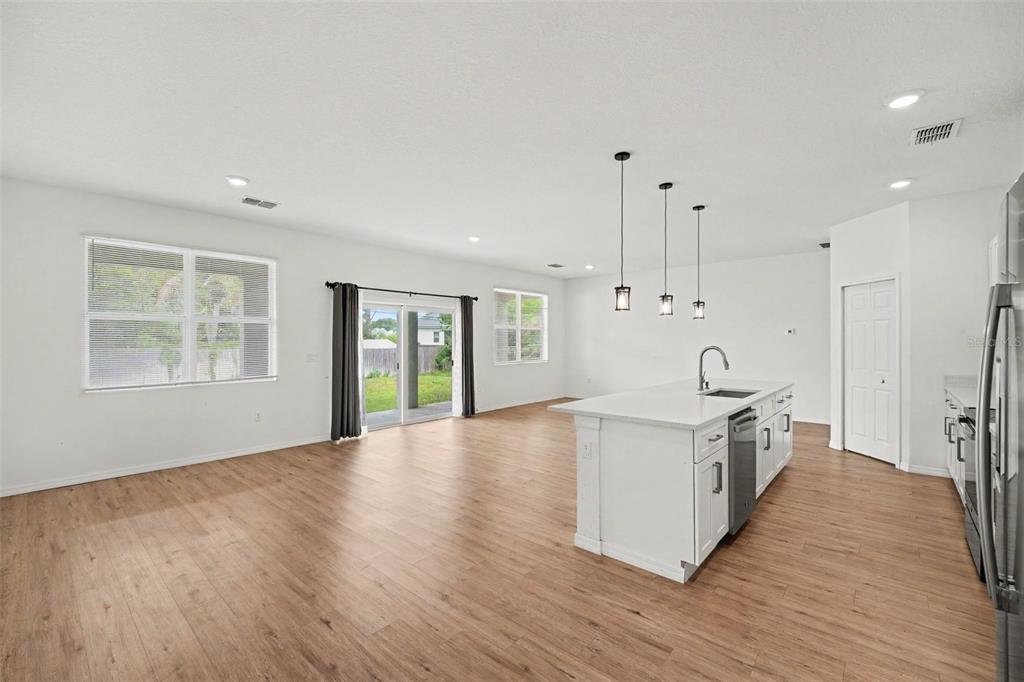 An open-concept kitchen and living area features light wood flooring, white cabinetry, and sliding doors — 333 KRASSNER DRIVE NW, PALM BAY, FL