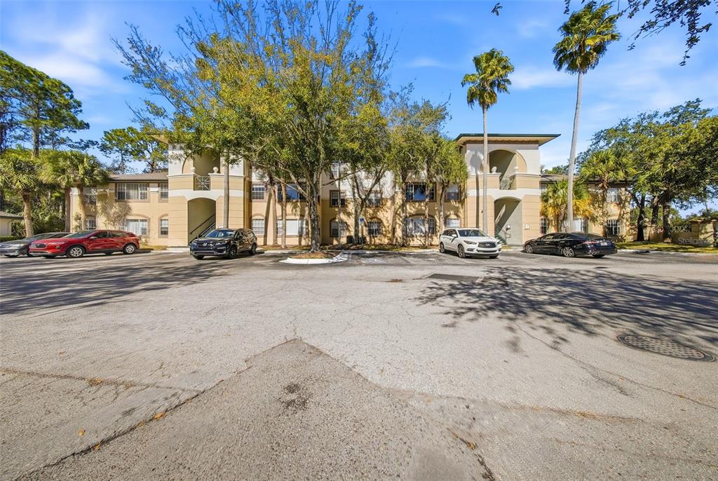 A multi-story apartment building with a parking lot in front under a blue sky — 17114 CARRINGTON PARK DRIVE UNIT 201, TAMPA, FL