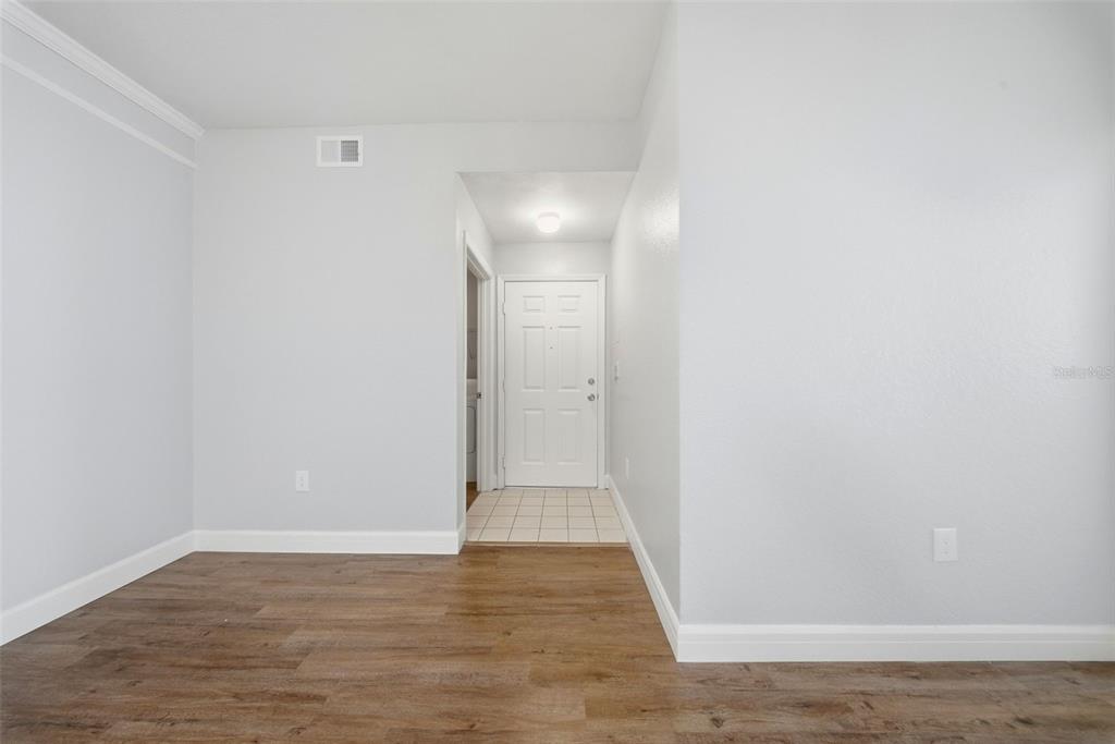A room with light gray walls, wood-look flooring, and a white door in the distance — 17114 CARRINGTON PARK DRIVE UNIT 201, TAMPA, FL