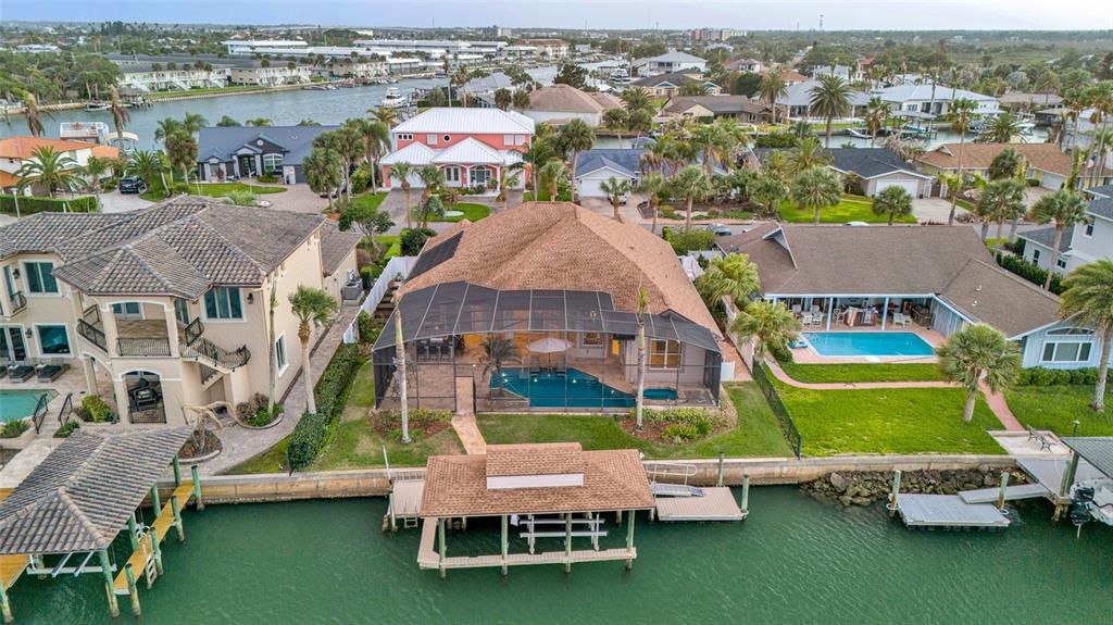An aerial view shows a waterfront house with a screened-in pool and a private dock — 133 VIA CAPRI, NEW SMYRNA BEACH, FL