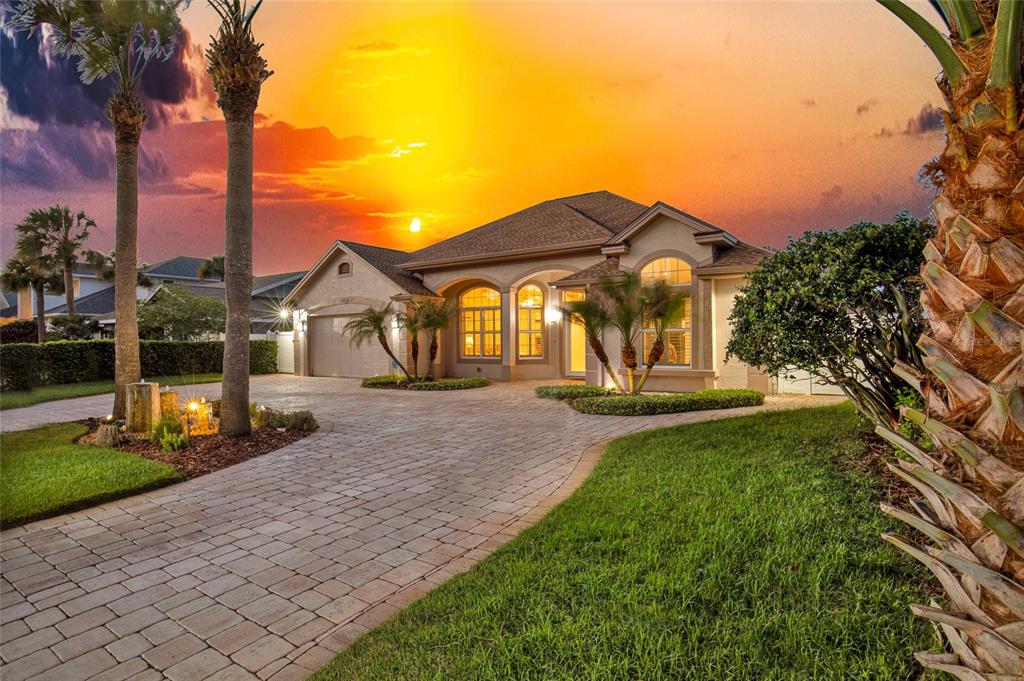 A single-story house with a paved driveway and palm trees at sunset — 133 VIA CAPRI, NEW SMYRNA BEACH, FL