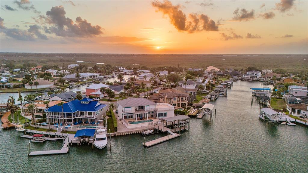 An aerial view of waterfront homes with private docks along a canal at sunset — 133 VIA CAPRI, NEW SMYRNA BEACH, FL