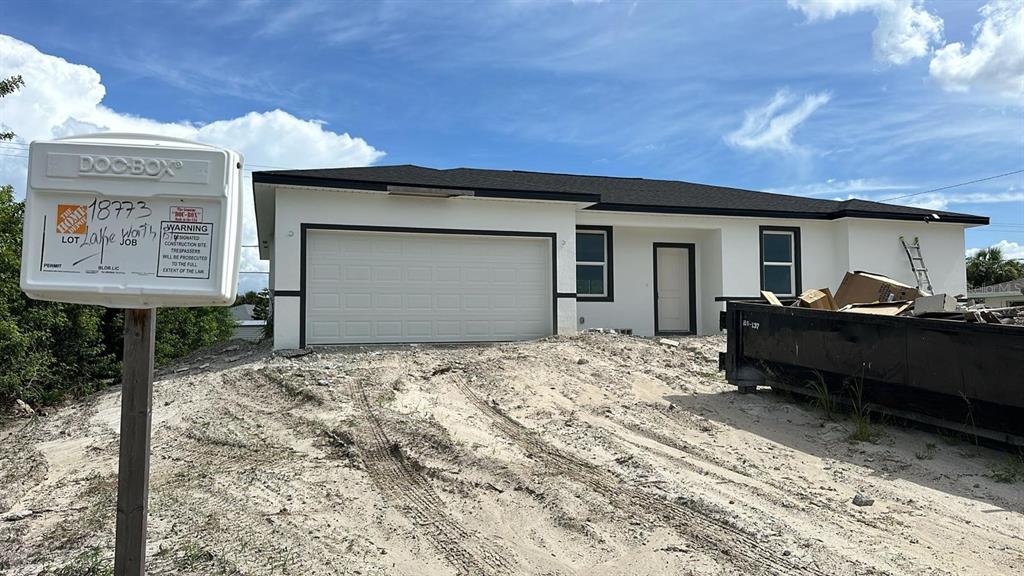 A newly constructed single-story house with a white exterior, black roof, and a dirt yard — 18773 LAKE WORTH BOULEVARD, PORT CHARLOTTE, FL