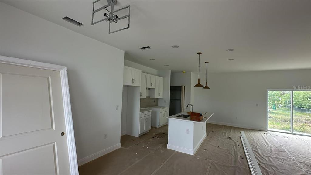 An unfinished kitchen features white cabinets, a central island, and pendant lighting under construction — 18773 LAKE WORTH BOULEVARD, PORT CHARLOTTE, FL