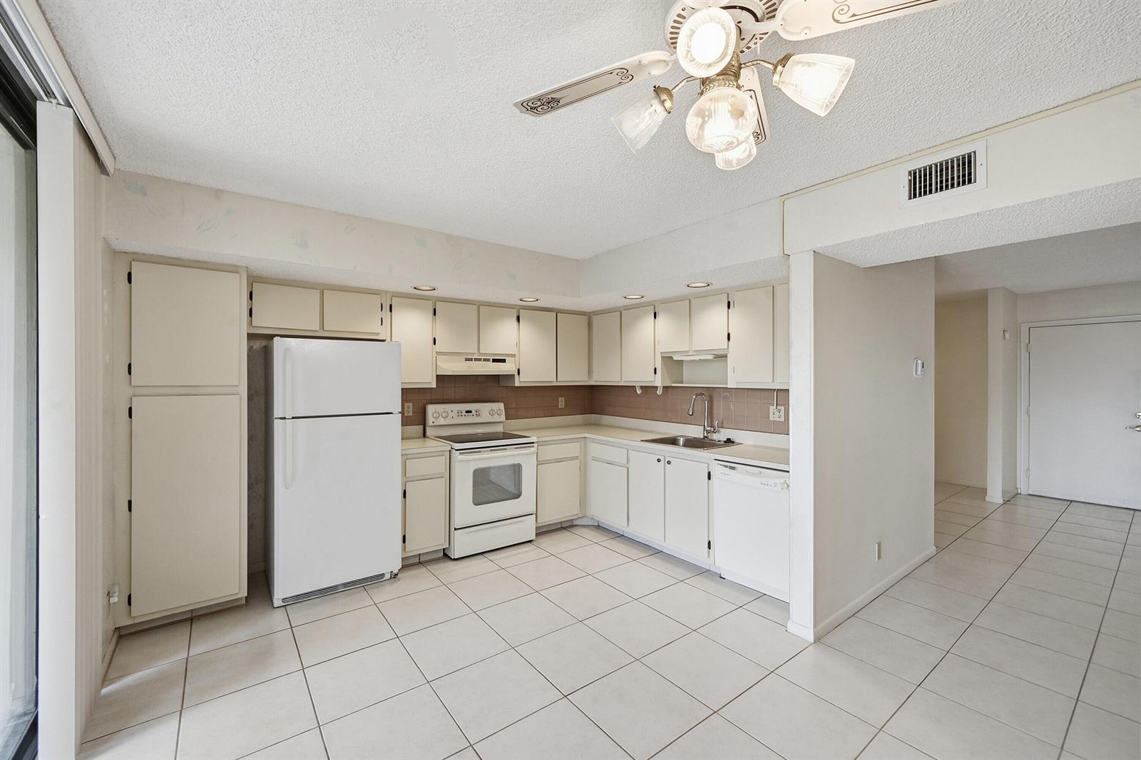 A kitchen with white cabinets, white appliances, and light-colored tile flooring — 5370 Las Verdes Circle # 219, Delray Beach FL 33484, DELRAY BEACH, FL