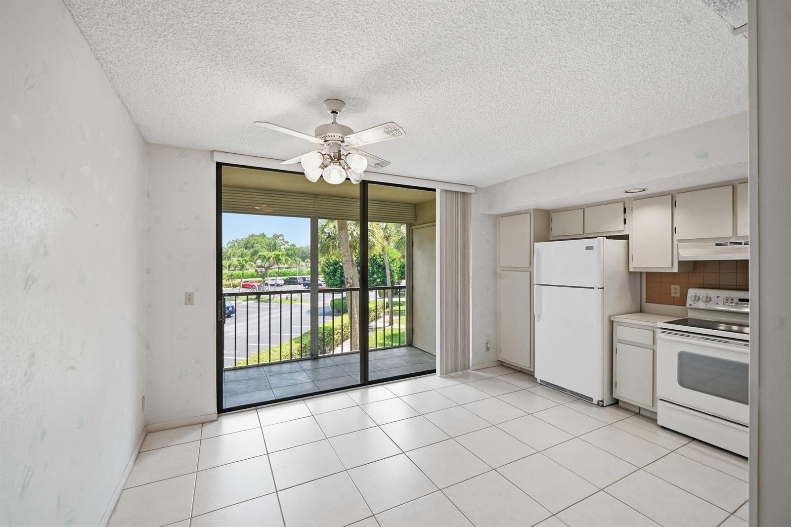A kitchen and dining area with white tile floors, white appliances, and a sliding glass door — 5370 Las Verdes Circle # 219, Delray Beach FL 33484, DELRAY BEACH, FL