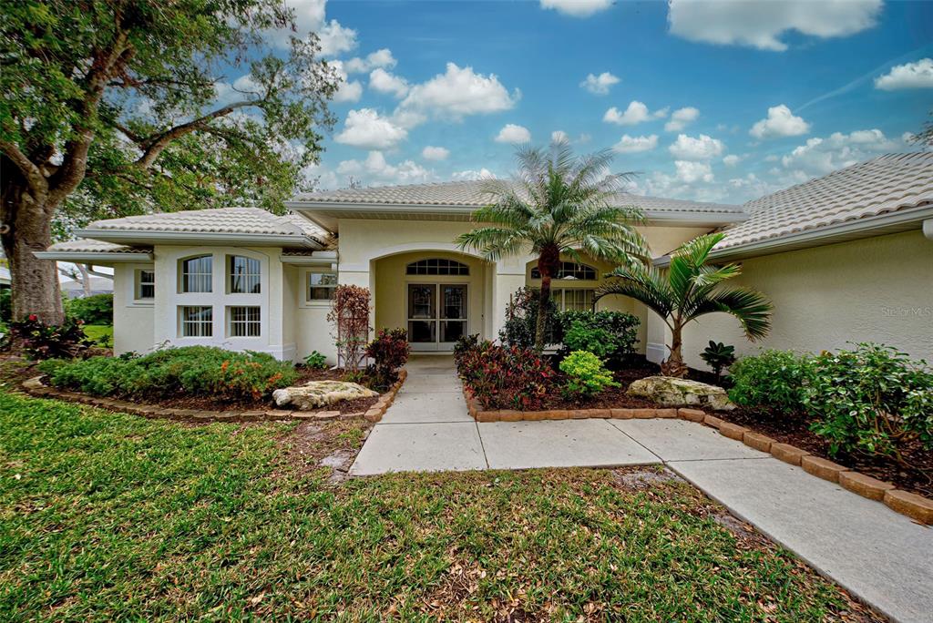 A single-story house with a light-colored exterior, a tiled roof, and a landscaped front yard — 339 MEADOW BEAUTY COURT, VENICE, FL