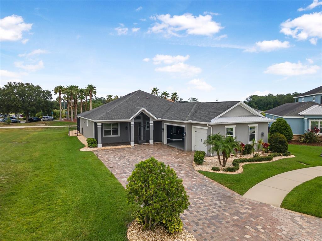 An exterior view of a gray single-story house with a paver driveway and attached garage — 2948 BELLA FLORE TERRACE, NEW SMYRNA BEACH, FL