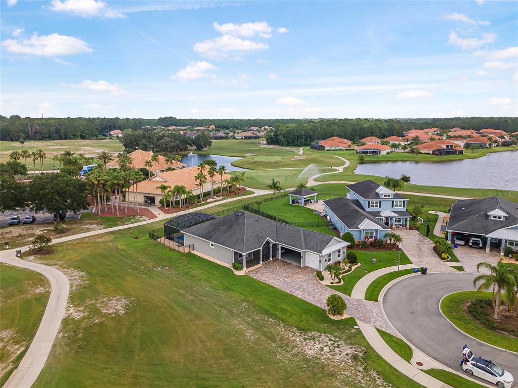 An aerial view shows a residential neighborhood with houses, a golf course, and a lake — 2948 BELLA FLORE TERRACE, NEW SMYRNA BEACH, FL