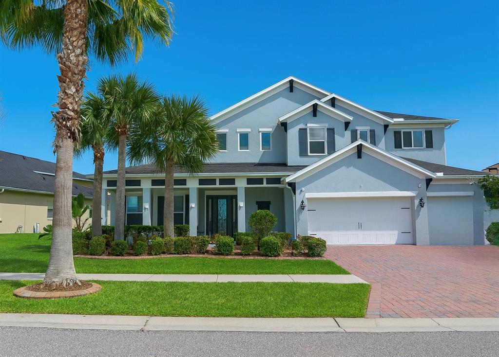 A two-story light blue house with a brick driveway and palm trees in the front yard — 11333 LAKE LUCAYA DRIVE, RIVERVIEW, FL