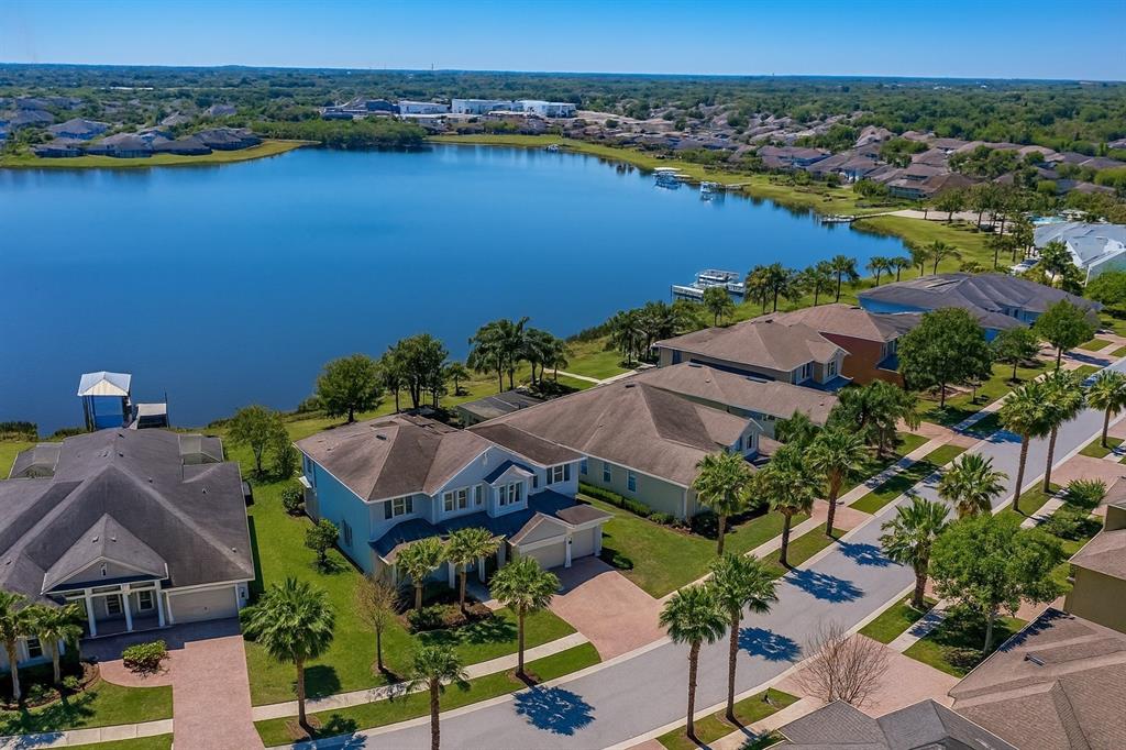 An aerial view shows suburban houses with brown roofs situated along a large lake — 11333 LAKE LUCAYA DRIVE, RIVERVIEW, FL