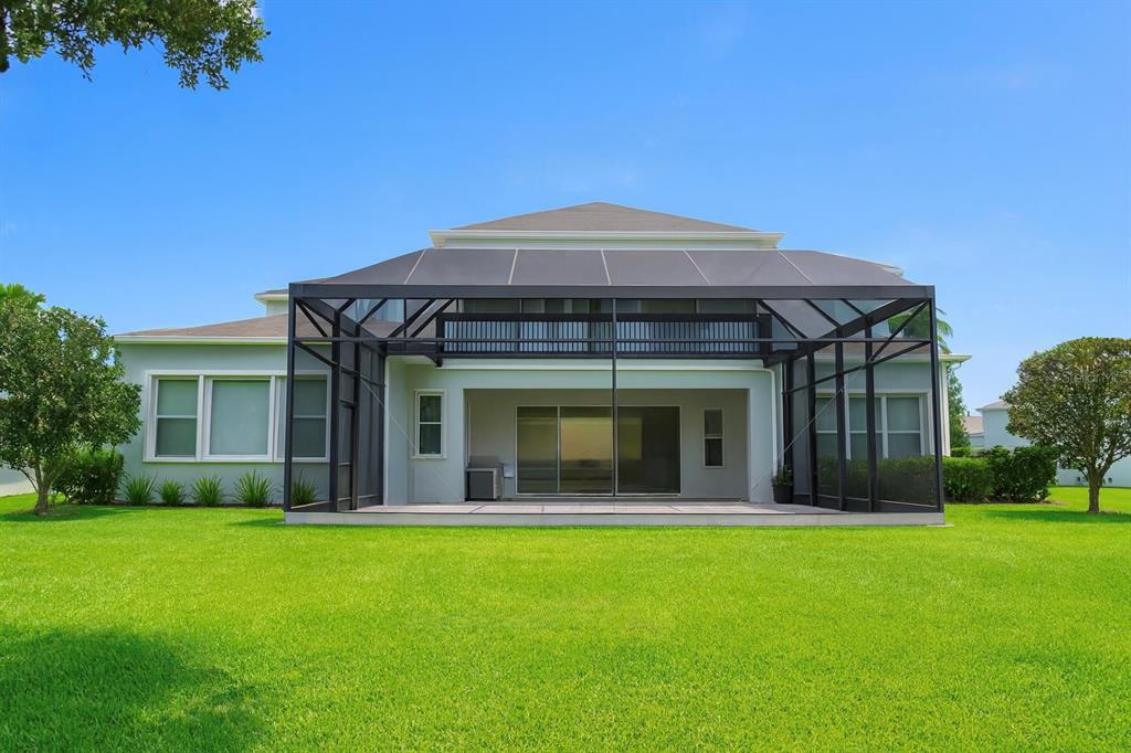 A house exterior featuring a large screened-in patio and a balcony overlooking a grassy lawn — 11333 LAKE LUCAYA DRIVE, RIVERVIEW, FL