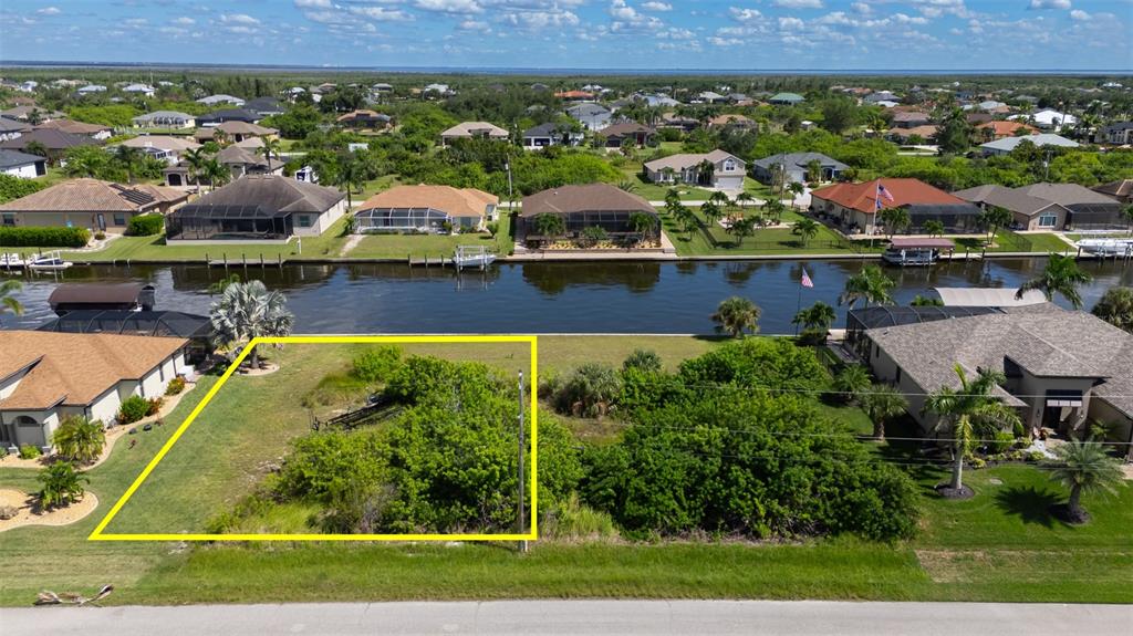 An aerial view shows a vacant, rectangular waterfront lot outlined in yellow — 8300 TECUMSEH CIRCLE, PORT CHARLOTTE, FL