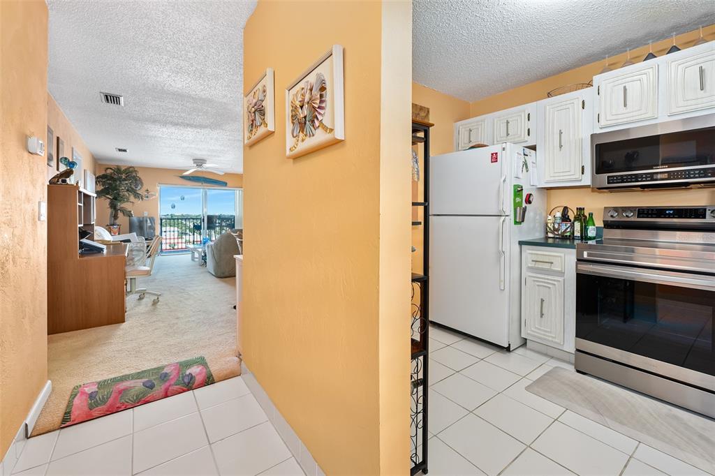 A view from a tiled kitchen looking into a carpeted living area with a balcony — 2711 N HALIFAX AVENUE UNIT 890, DAYTONA BEACH, FL