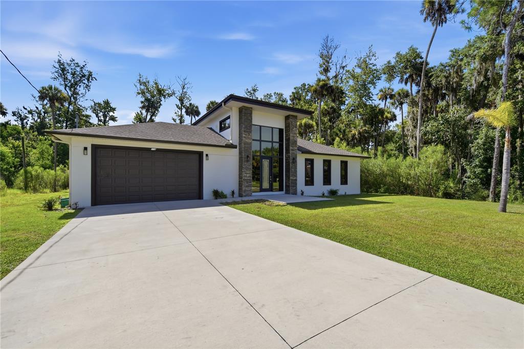A modern single-story house with a two-car garage and a stone-accented entryway — 118 BLARE DRIVE, PALM COAST, FL