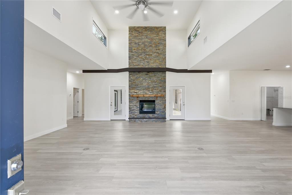 A spacious living room features light wood flooring, a stone fireplace, and high vaulted ceilings — 118 BLARE DRIVE, PALM COAST, FL