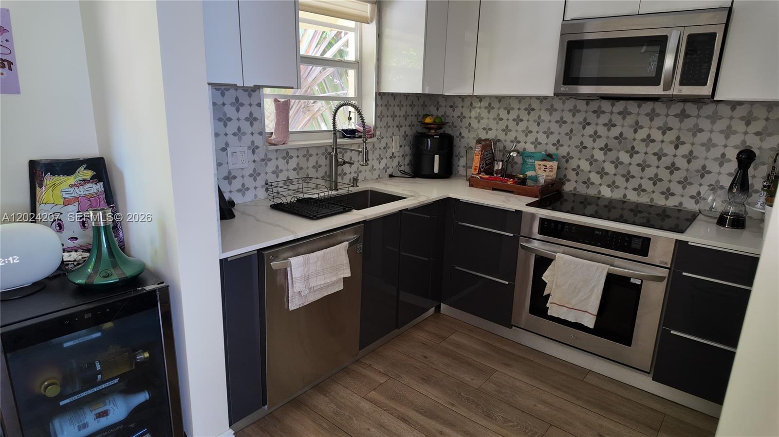A modern kitchen features dark gray lower cabinets, white upper cabinets, and a patterned backsplash — 1535 Meridian Ave # 6, Miami Beach FL 33139, MIAMI BEACH, FL