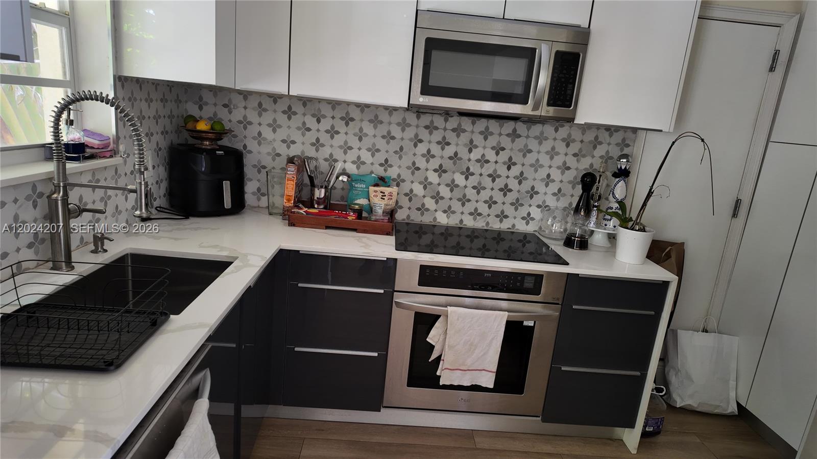 A modern kitchen features white upper cabinets, dark lower cabinets, and a patterned tile backsplash — 1535 Meridian Ave # 6, Miami Beach FL 33139, MIAMI BEACH, FL