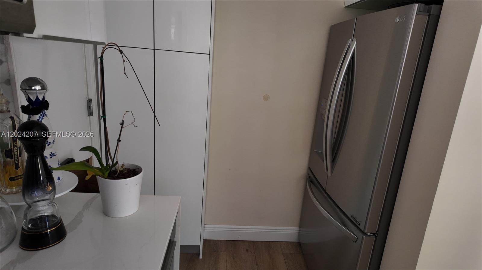 A kitchen features a stainless steel refrigerator, white cabinetry, and a potted orchid on a counter — 1535 Meridian Ave # 6, Miami Beach FL 33139, MIAMI BEACH, FL