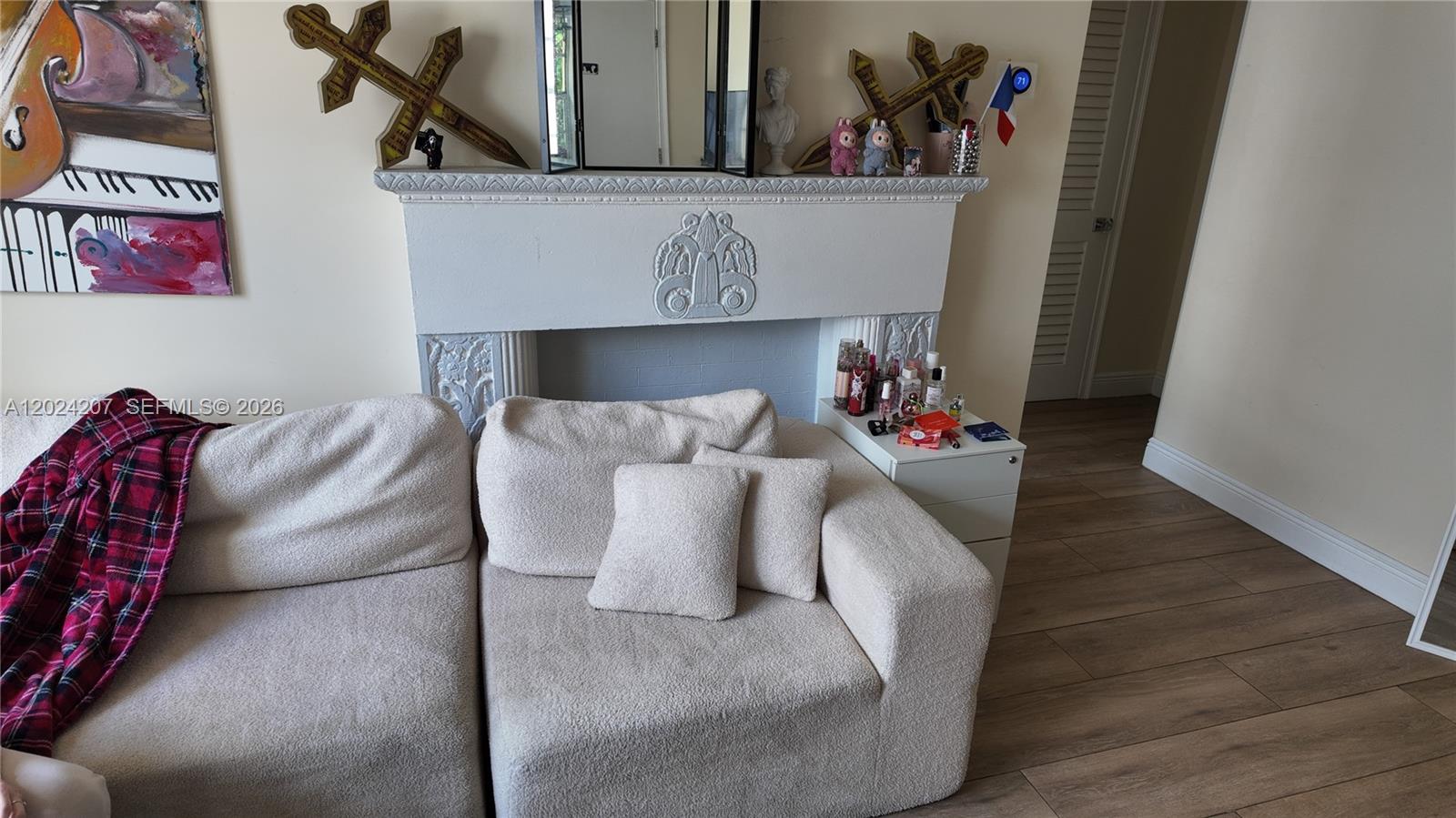 A living room features a white fireplace mantel, a textured sofa, and decorative wall art — 1535 Meridian Ave # 6, Miami Beach FL 33139, MIAMI BEACH, FL