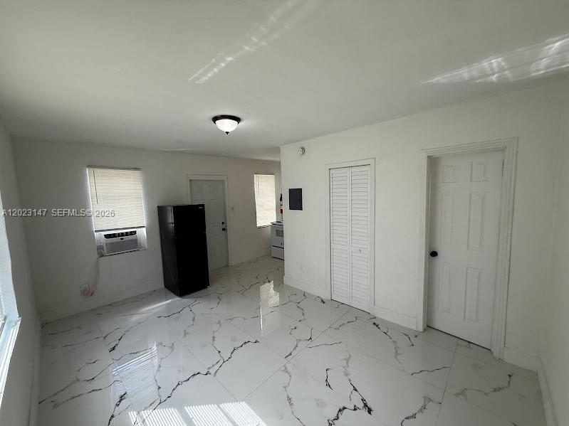 A room with white walls, white marble-patterned tile flooring, a black refrigerator, and two doors — 2773 NW 57th St, Miami FL 33142, MIAMI, FL