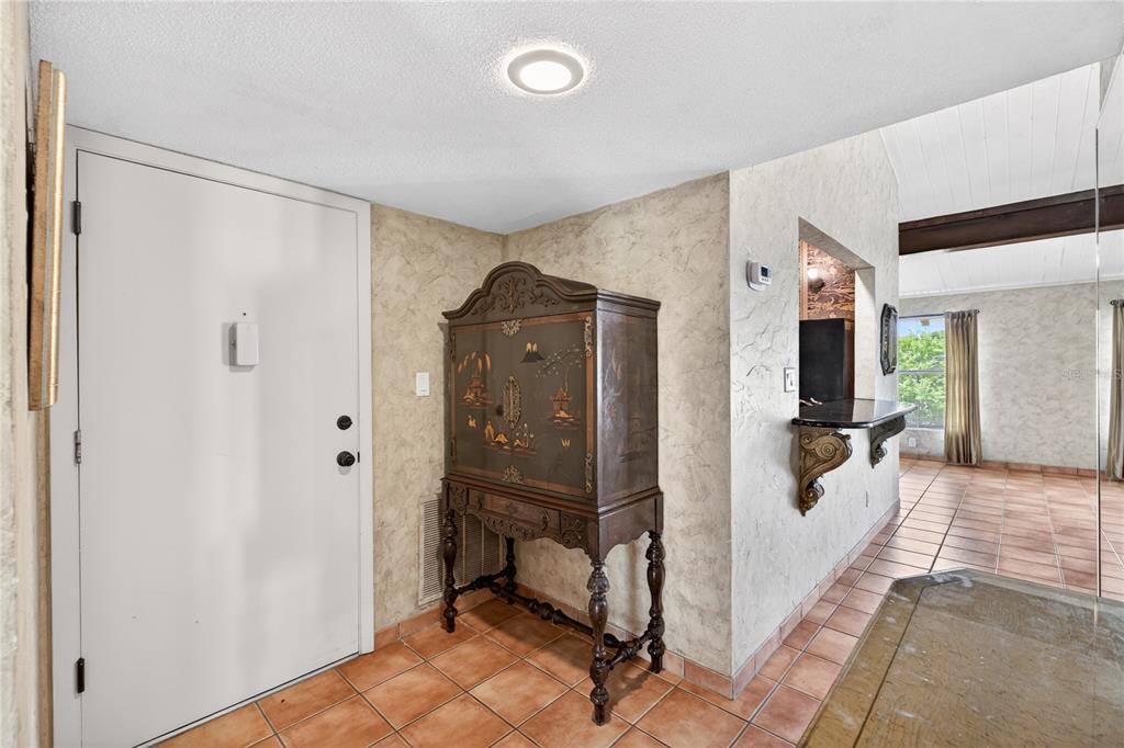 An entryway features a white door, a decorative wooden cabinet, and light-colored tiled flooring — 200 MAITLAND AVENUE UNIT 128, ALTAMONTE SPRINGS, FL