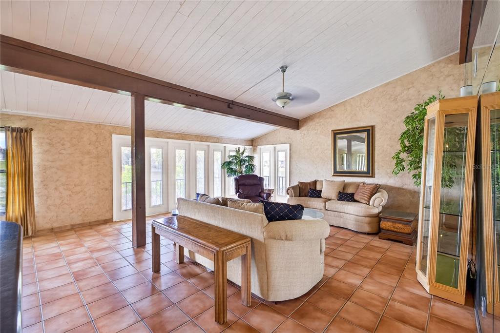 A living room with tile floors, a wood-beamed ceiling, and a wall of glass doors — 200 MAITLAND AVENUE UNIT 128, ALTAMONTE SPRINGS, FL