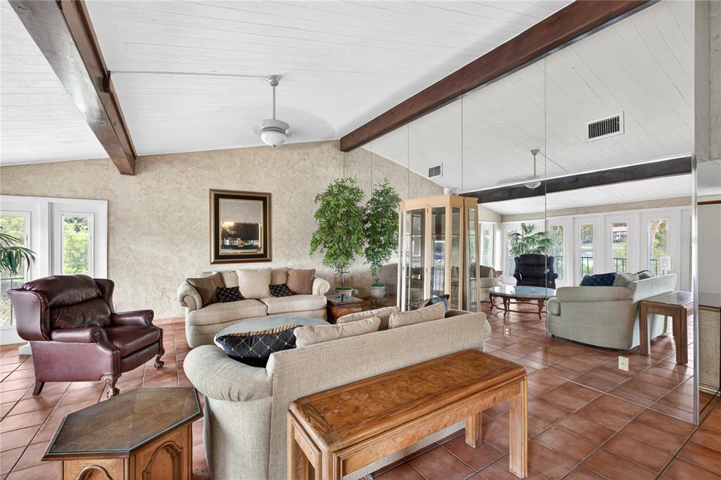 A living room features vaulted ceilings with exposed beams, tiled floors, and a mirrored wall — 200 MAITLAND AVENUE UNIT 128, ALTAMONTE SPRINGS, FL