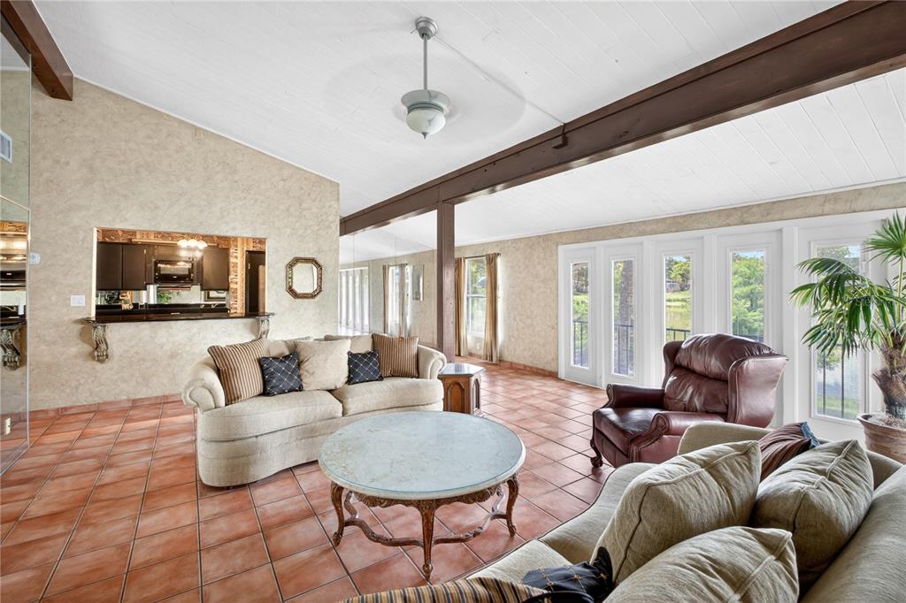 A living room features tile floors, a vaulted ceiling with exposed beams, and glass doors — 200 MAITLAND AVENUE UNIT 128, ALTAMONTE SPRINGS, FL